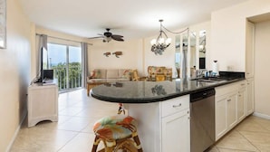 A spacious kitchen with a large island, a dining area with a sofa, and a balcony with a view. - Stay and Play, Enjoy Scenic Views at Ocean Pointe 5312 (Tavernier)