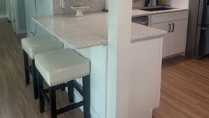 A kitchen with white cabinets, a granite countertop, and wooden flooring.
