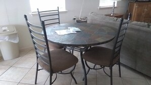 A dining table with chairs, a trash bin, a couch, and a lamp. - Casa Tranquilla: Scenic Solar and Wind Powered Home (Alpine)