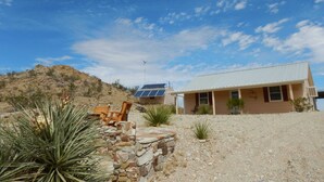 A house with a stone wall, a wooden bench, and a hill in the background. - Casa Tranquilla: Scenic Solar and Wind Powered Home (Alpine)
