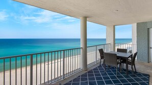 A balcony with a view of the ocean, a table with chairs, and a patterned floor. - Oceanfront 2-bedroom condo in Panama City Beach, sleeps 8, ideal for families. (Panama City Beach)