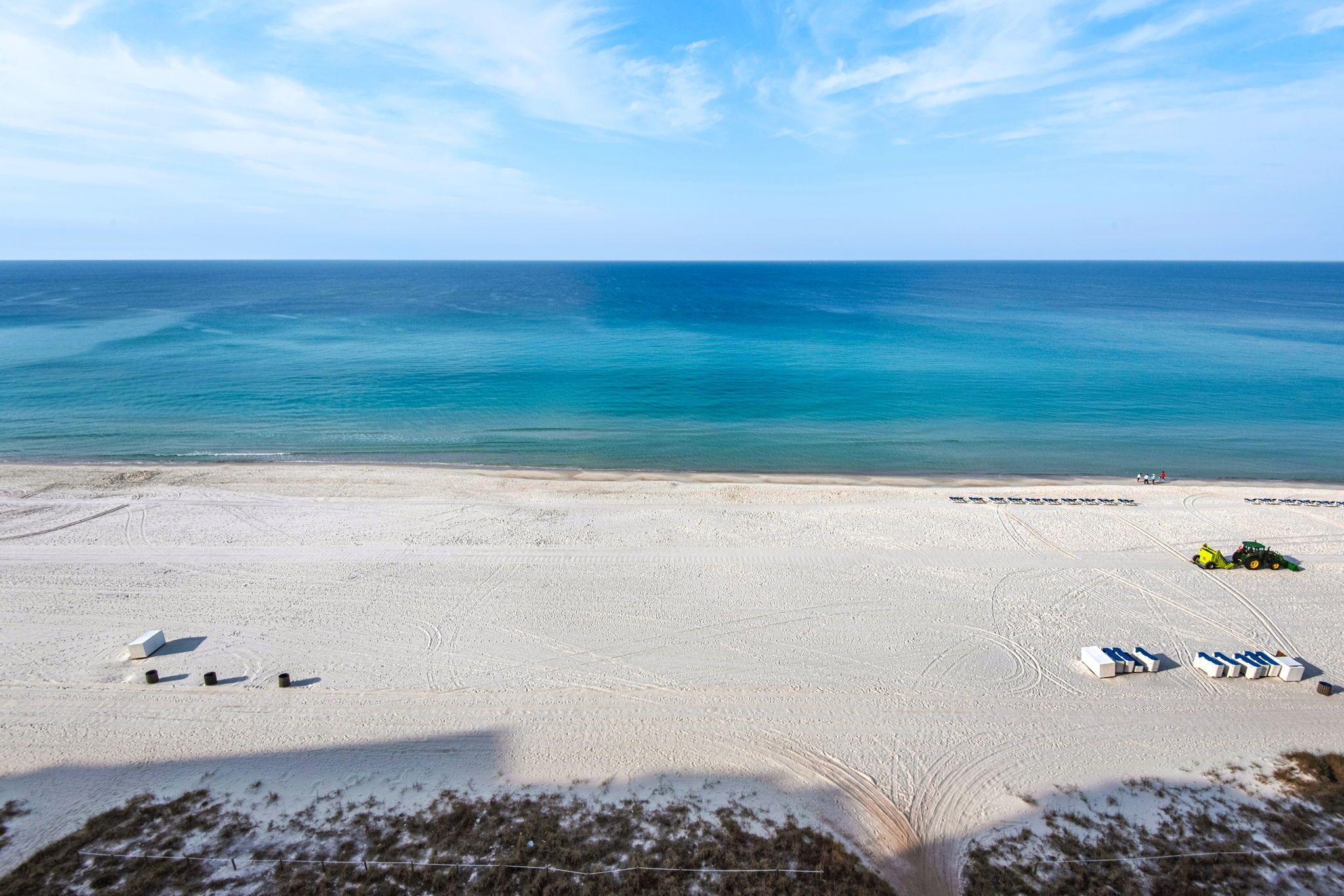 En strand med fri utsikt över havet, en sandstrand och några strandstolar.