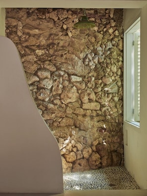 Enjoy a room with a window offering views, a textured stone wall, and a patterned tile floor.