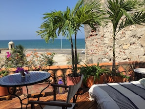 Enjoy the serene sea view from this outdoor space, featuring a table, chair, and lush greenery.