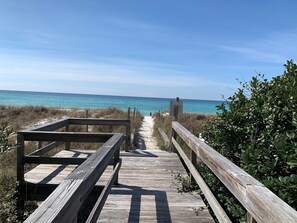 Une promenade en bois mène à une plage, et un panneau indique qu’il s’agit d’une zone protégée.