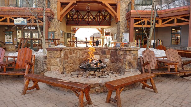 An outdoor seating area with wooden benches and a stone fire pit.
