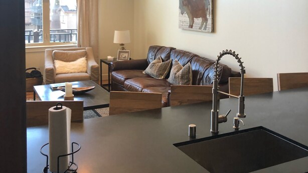 A modern living room with a sofa, a coffee table, and a kitchen area with a sink and countertop. - Luxury 2 Bedroom, 2 Bath Condo - Perfect for a Fun Filled Family Get Away! (Mammoth Lakes)