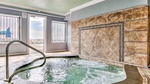 Un espace spa comprenant un jacuzzi, une vue sur la ville et un grand mur recouvert de carreaux.