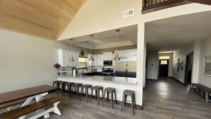 Une cuisine moderne dotée d’un îlot central, de tabourets de bar et d’un banc en bois.