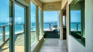 A corridor with large windows leading to a deck with a view of the sea. - Captain's Quarters (Santa Cruz)