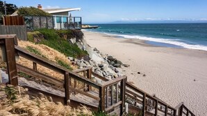 A beachside property with a wooden staircase leading to a glass-enclosed balcony overlooking the ocean. - Captain's Quarters (Santa Cruz)