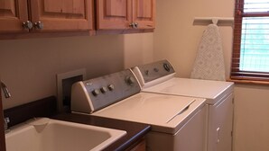 A kitchen with wooden cabinets, a stove, a washing machine, and a window with blinds. - This beautiful, spacious condo is located right off Main Street in Ouray. (Ouray)