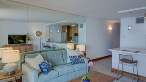 A modern living room with a sofa, coffee table, and a dining area with a chair.
