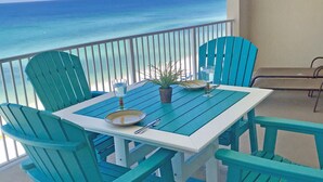 A turquoise deck with a table and chairs, overlooking a clear blue ocean. - LUXURIOUS CONDO ON THE BEACH includes FREE BEACH CHAIRS. (Panama City Beach)