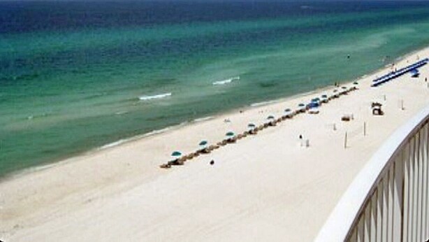 A beach with a clear view of the ocean, a sandy shore, and a row of umbrellas. - LUXURIOUS CONDO ON THE BEACH includes FREE BEACH CHAIRS. (Panama City Beach)