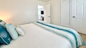 A bedroom with a bed, pillows, a ceiling fan, and a door. - JULY 2026 NEW REMODEL... Mermaid`s Cove, Nestled between Beach and Bay! (San Diego)