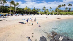 A beach with clear water, palm trees, and people.