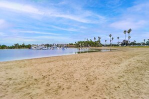 A beach with a marina, palm trees, and a building with a large window.