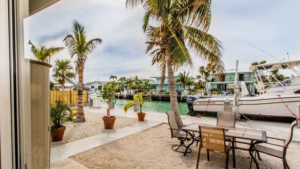 A marina with boats, palm trees, and a patio area with chairs and tables. - Doc's Holiday updated 2bed/2bath half duplex with Cabana Club (Key Colony Beach)