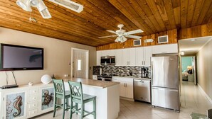 A modern kitchen with a central island, white cabinetry, and a ceiling fan. - Doc's Holiday updated 2bed/2bath half duplex with Cabana Club (Key Colony Beach)