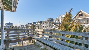 A wooden pier with benches overlooking a waterfront with houses in the background. - Marina view one bedroom cottage close to amenities on BHI. Walking distance to the NC lighthouse (Bald Head Island)
