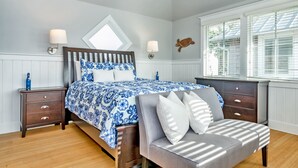 A bedroom with a bed, nightstands, a bench, and a turtle decoration on the wall. - Marina view one bedroom cottage close to amenities on BHI. Walking distance to the NC lighthouse (Bald Head Island)