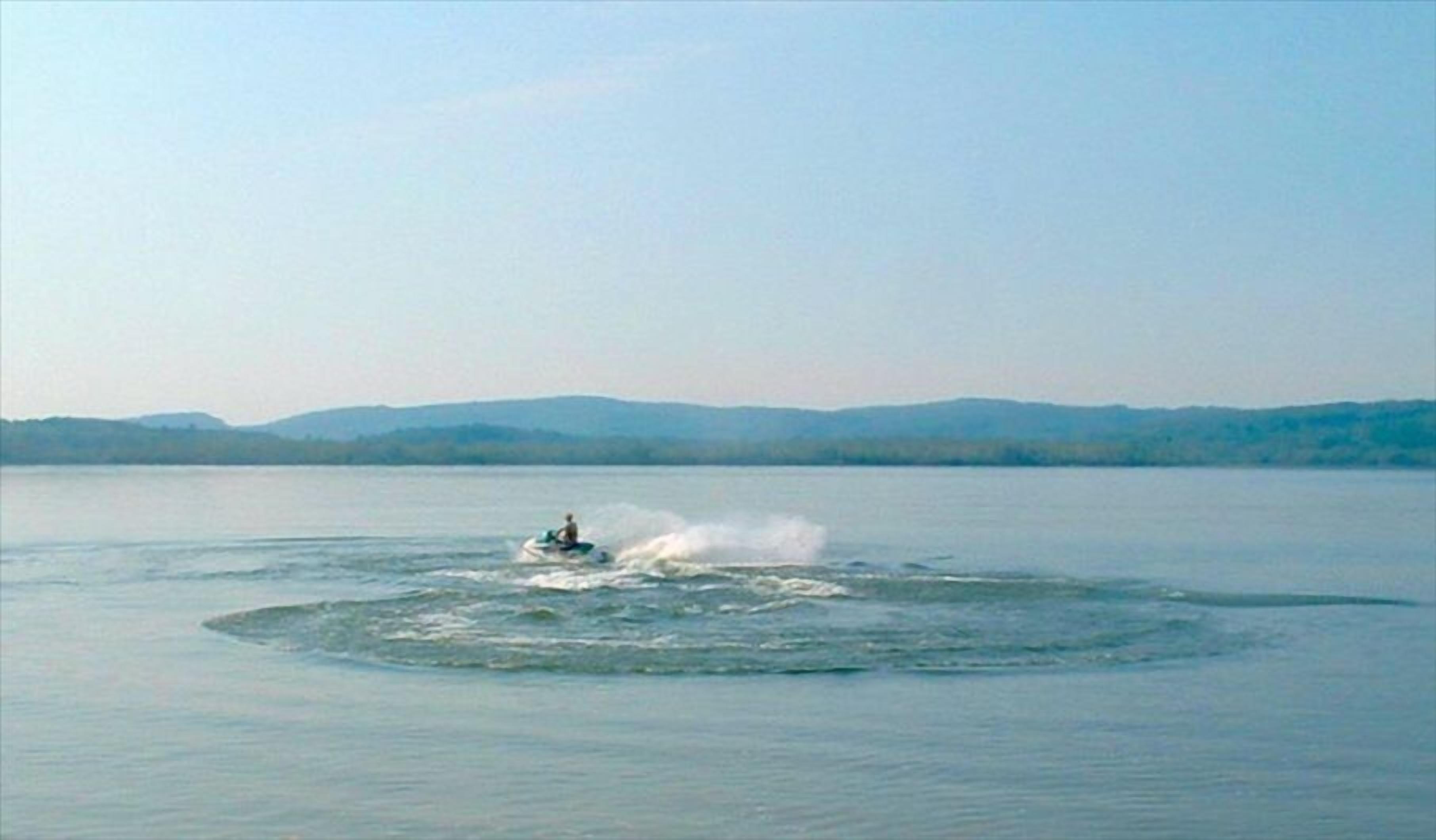 A body of water with a person jet-skiing.