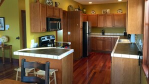 Una cucina con mobili in legno, un'isola centrale, un forno a microonde, un fornello e un frigorifero.