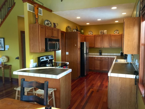Una cocina con armarios de madera, una isla central, un microondas, una estufa y un refrigerador.
