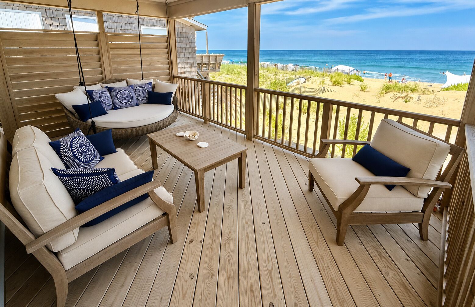 Une terrasse en bois avec un canapé, des chaises et une table, donnant sur une plage.
