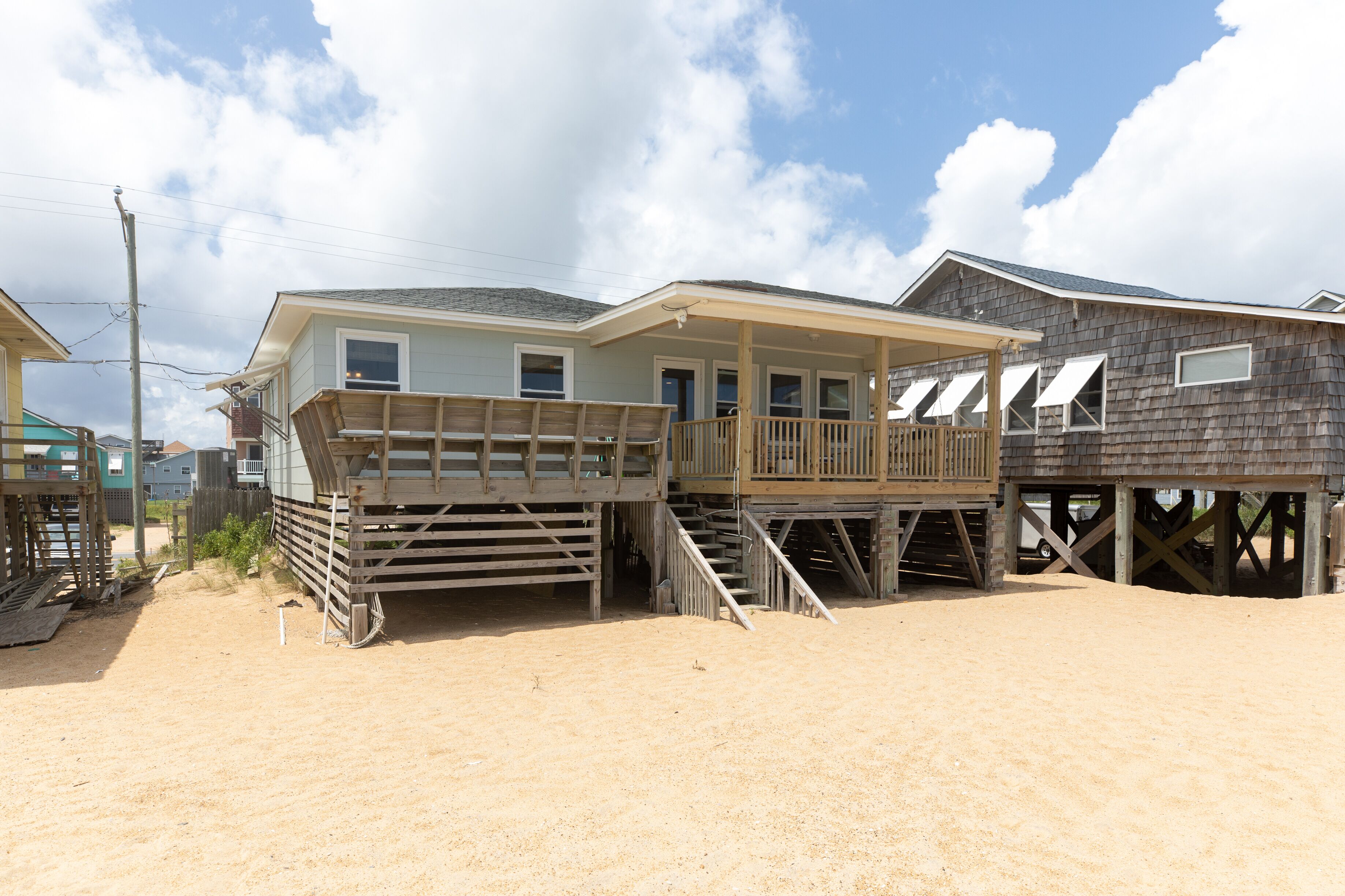 A beachfront house with a wooden deck and a covered porch.