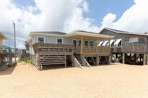 A beachfront house with a wooden deck and a covered porch.