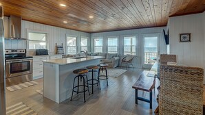 Una cocina amplia con techo de madera, una isla grande con taburetes y vistas al exterior.