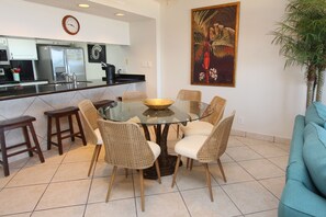 Una cocina moderna con un refrigerador de acero inoxidable, una cafetera y un reloj en la pared.
