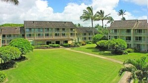 Un hôtel composé de plusieurs bâtiments à étages, doté d’une pelouse bien entretenue et d’un aménagement paysager de style tropical.