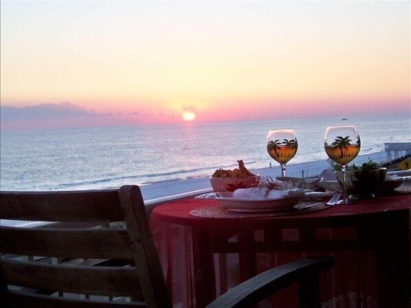 A table with a red tablecloth, two wine glasses, and a bowl of food set against a sunset view. - Pets (dogs)Welcome *  Sea 4 Miles*  Sea 4 Yourself* Maravilla 2301 (Destin)