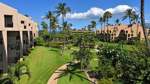 A resort with multiple buildings, palm trees, and a well-maintained lawn. - Kam Sands -Innercourt- Ocean views- large lanai & very private third floor end  (Kihei)