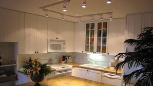 A kitchen with white cabinets, a microwave, a stove, and a sink. - Kam Sands -Innercourt- Ocean views- large lanai & very private third floor end  (Kihei)