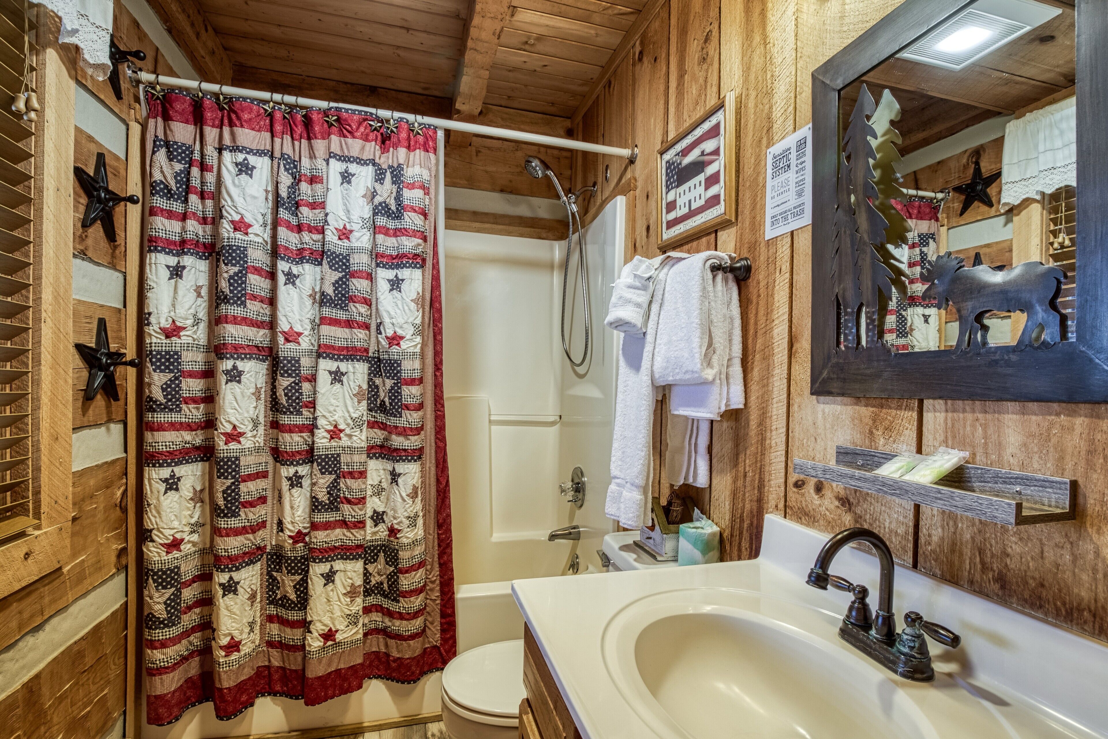 A bathroom with a wooden interior, a white sink, a mirror, and a shower curtain with a star pattern.