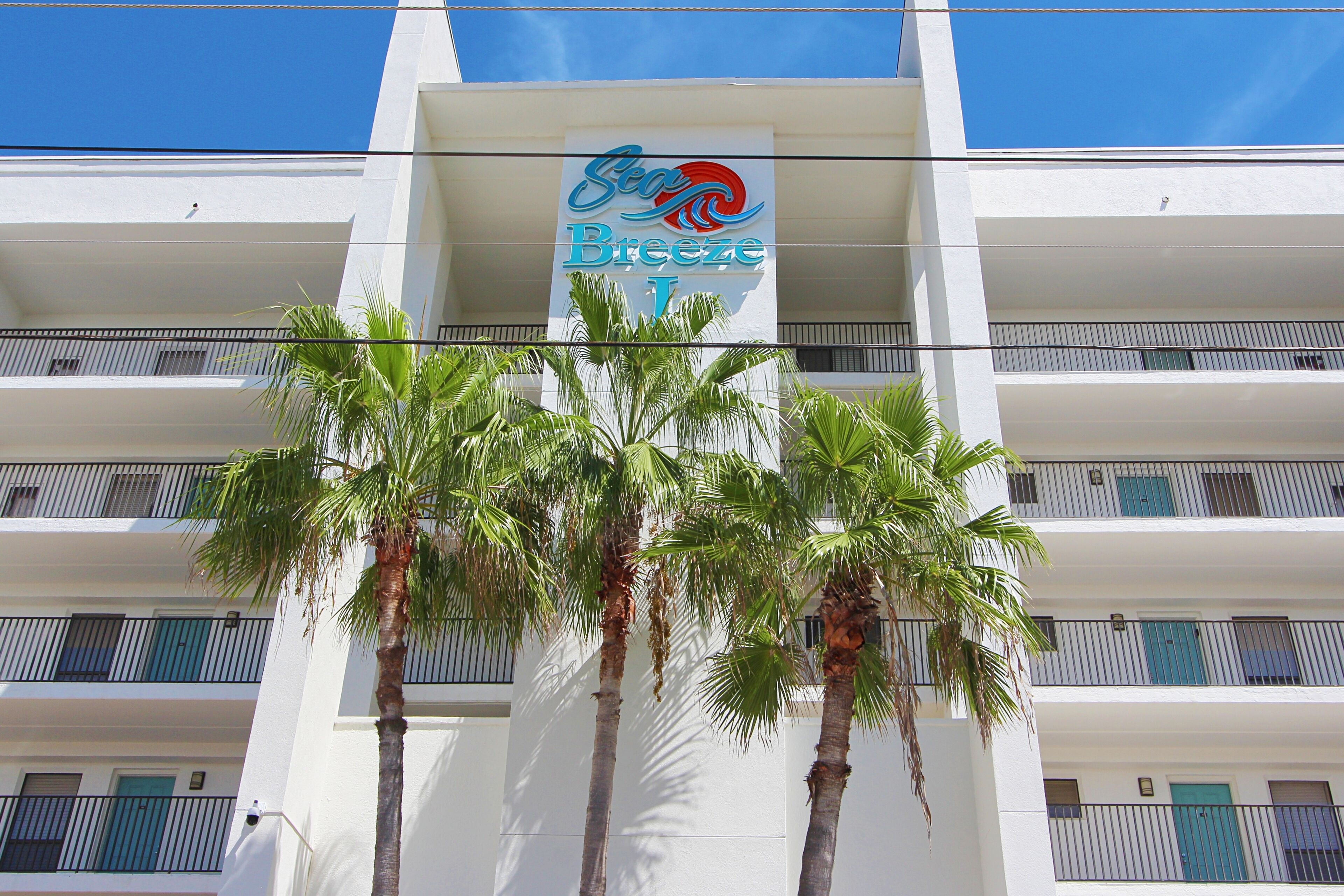Un hotel con un cartel que dice "Breeze I" y varios balcones con puertas azules.
