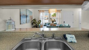 A kitchen with granite countertops, stainless steel sinks, and wooden cabinets. - Beach Rendezvous-Beachside Complex with a Pool (Navarre)