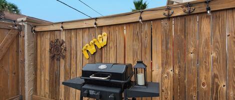 A backyard with a wooden fence, a barbecue grill, and a lantern.