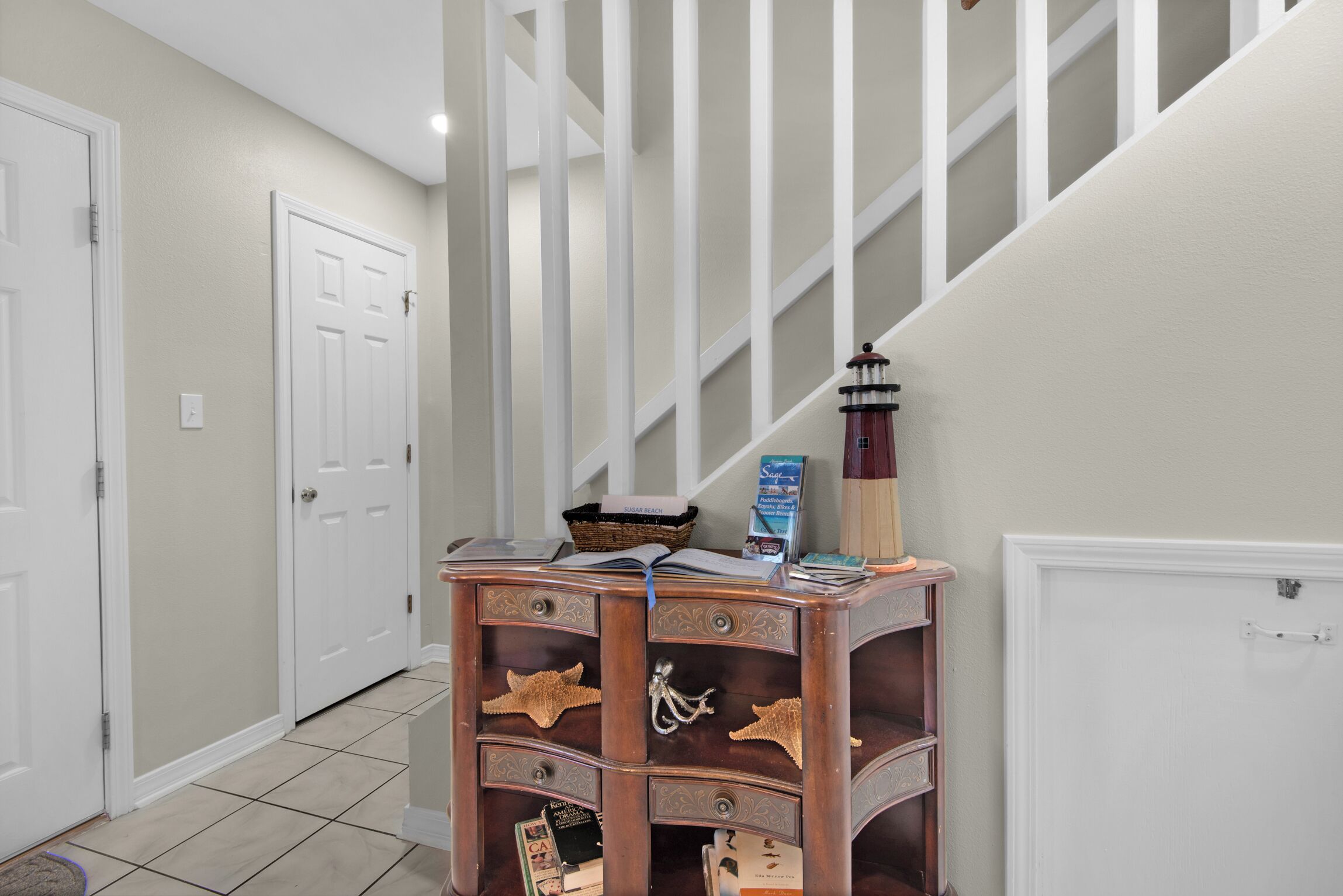 A hallway with a wooden sideboard, a staircase, and a white door.