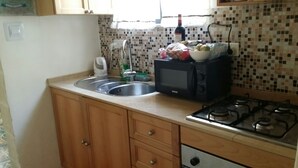 A small kitchen with a sink, a microwave, a gas stove, and wooden cabinets.