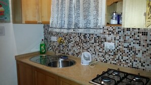 A kitchen with a sink, a coffee maker, and a gas stove.