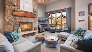Una sala de estar acogedora con chimenea de piedra, asientos confortables y ventanas amplias que ofrecen vistas al exterior.
