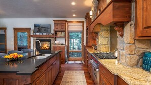 Una cocina con armarios de madera, una chimenea de piedra y una isla grande con un cuenco de frutas.