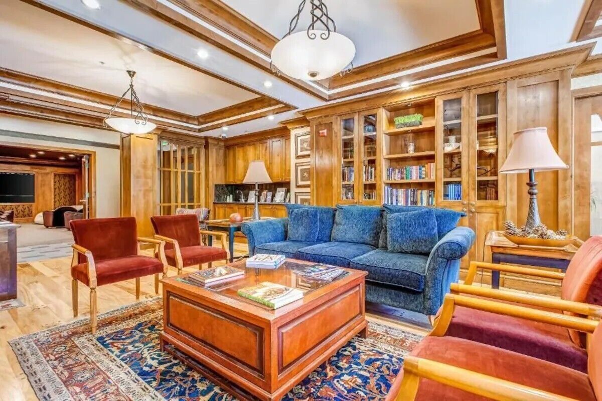 A spacious library with wooden bookshelves, a blue sofa, and red chairs.