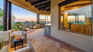 A covered outdoor patio with stone flooring, wicker furniture, and a view of the landscape. - LUXURY 5 acre Property Heated Pool ~ See our Reviews!! (Scottsdale)