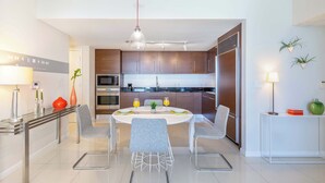 A modern kitchen with a central island, stainless steel appliances, and a dining area with a round table and four chairs. - Riverwalk Chic Suite | Brickell's High Walk Score (Miami)